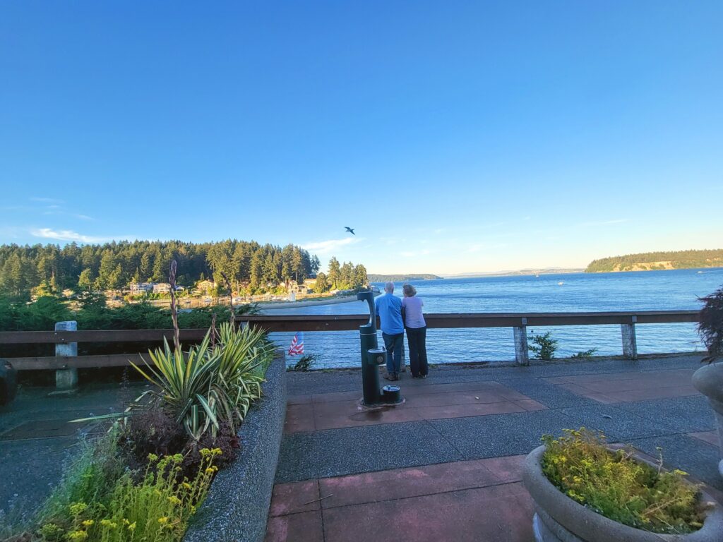 Retired couple looks out over Gig Harbor entrance with Vashon island in the background